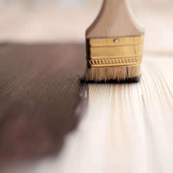 Un pennello viene utilizzato per dipingere un pavimento in legno.