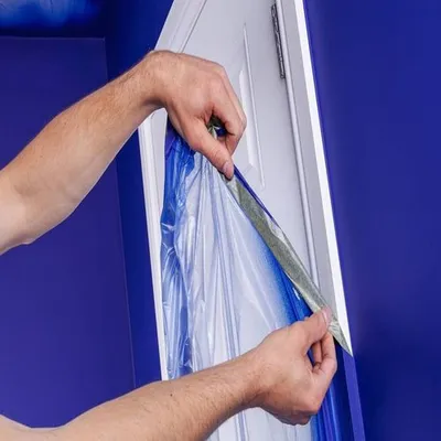 Un uomo scopre una porta dopo aver pitturato la parete blu.